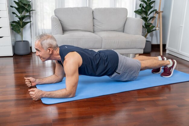 Foto homem sênior atlético e esportivo pranchando no tapete de exercícios físicos em casa, exercício como conceito de estilo de vida corporal saudável após a aposentadoria clout