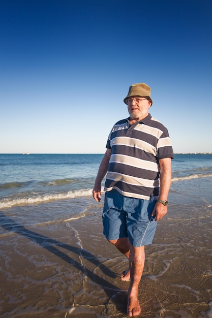 Homem sênior caminhando na praia