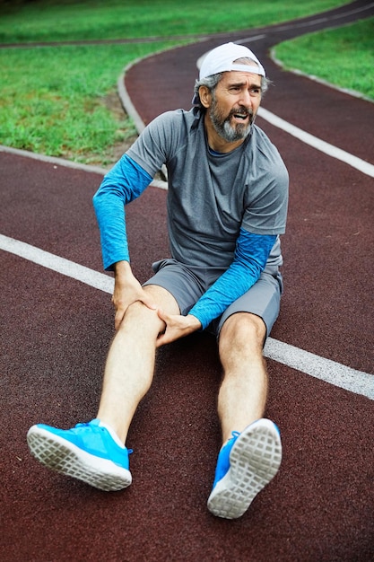 Homem sênior com lesão enquanto corre na pista