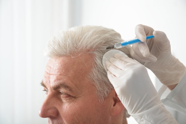 Foto homem sênior com problema de perda de cabelo recebendo injeção no salão closeup