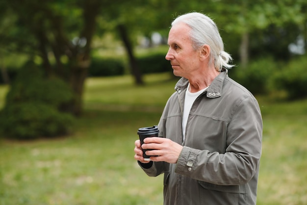 Homem sênior com roupa elegante, segurando a xícara de café