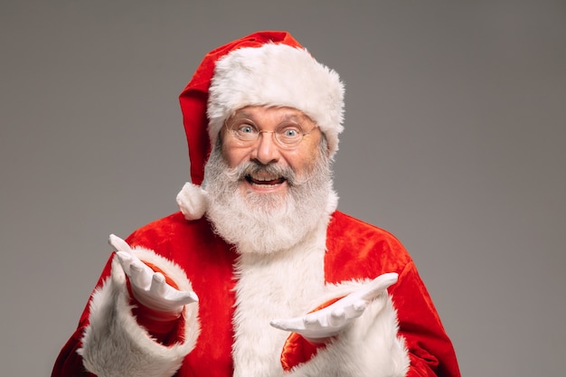 Homem sênior como Papai Noel, isolado no fundo cinza do estúdio. Modelo masculino barbudo caucasiano em traje tradicional. Ano novo 2021, presentes, feriados, clima de inverno. Copyspace para seu anúncio. Ressaca
