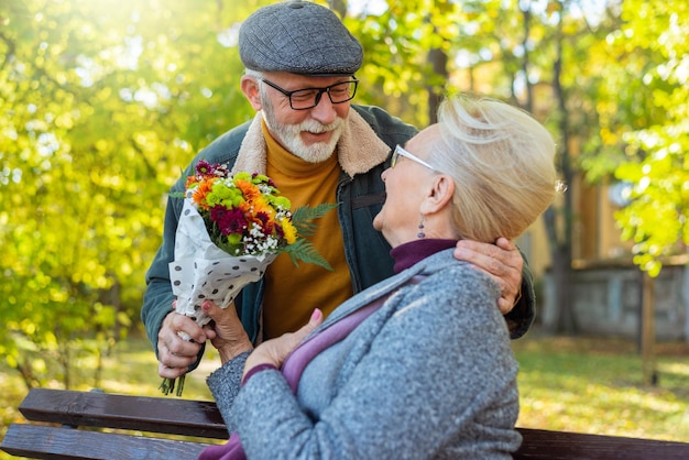 Homem sênior dando flores para sua esposa no parque