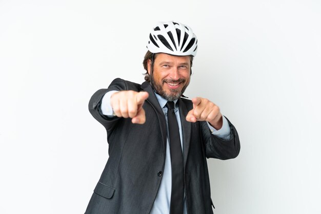 Homem sênior de negócios com um capacete de bicicleta isolado no fundo branco aponta o dedo para você enquanto sorri