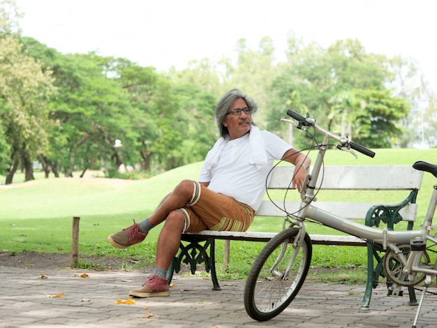 Homem sênior descansar no parque depois de andar de bicicleta