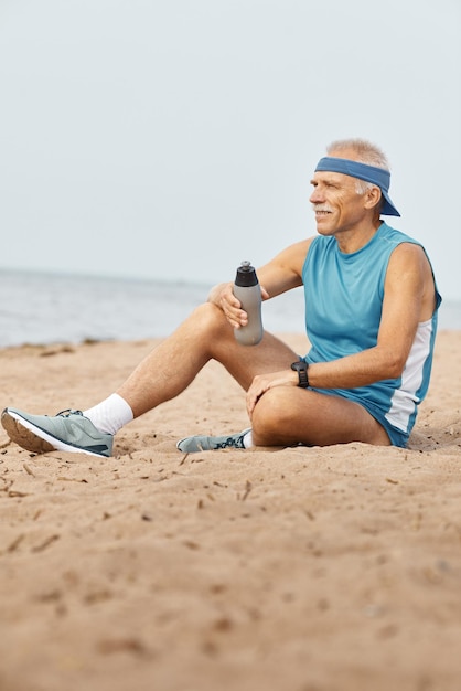 Homem sênior desportivo relaxante com garrafa de água