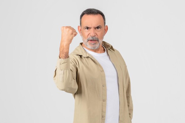 Foto homem sênior determinado fazendo um punho em fundo branco