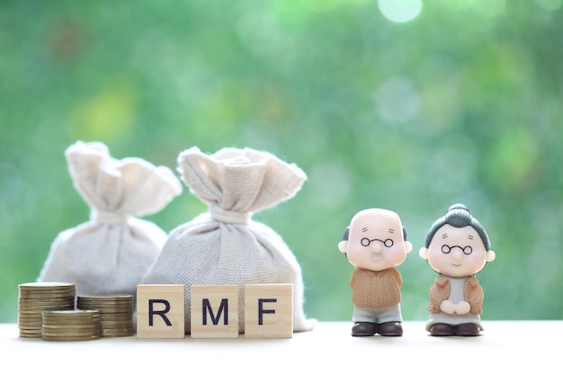 Homem sênior do Fundo Mútuo de Aposentadoria RMF com palavra RMF e pilha de moedas dinheiro em fundo verde natural Economize dinheiro para se preparar no futuro e no conceito de aposentadoria de pensão