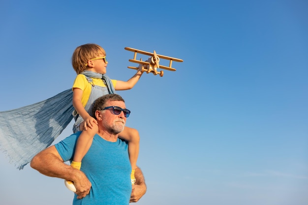 Homem sênior e criança brincando ao ar livre contra o fundo do céu de verão Avô e menino se divertindo juntos Conceito de férias em família Feliz dia dos pais