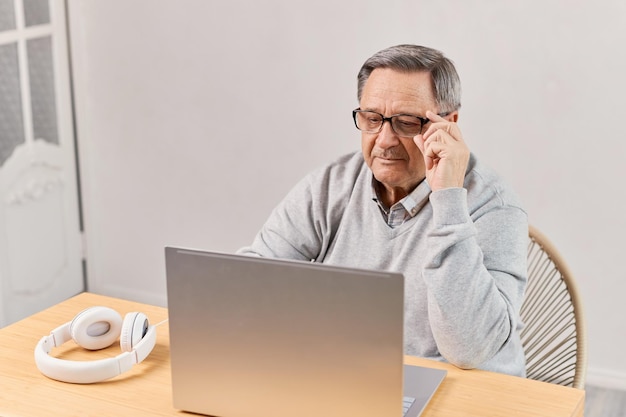 Homem sênior em casa conectado no computador portátil