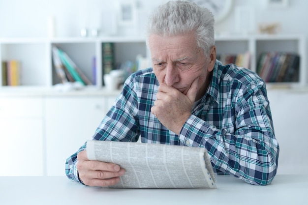 Homem sênior em casa homem sênior lendo jornal em casa