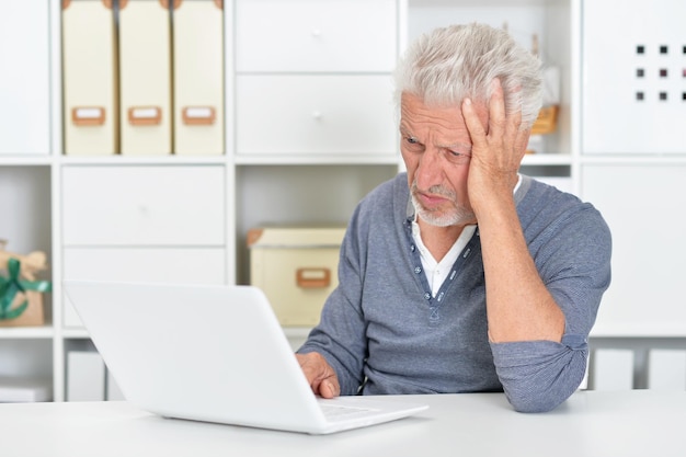 Homem sênior emocional usando laptop