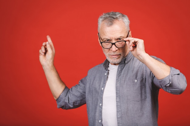 Foto homem sênior envelhecido usando óculos enquanto apresenta com a mão e apontando com o dedo.