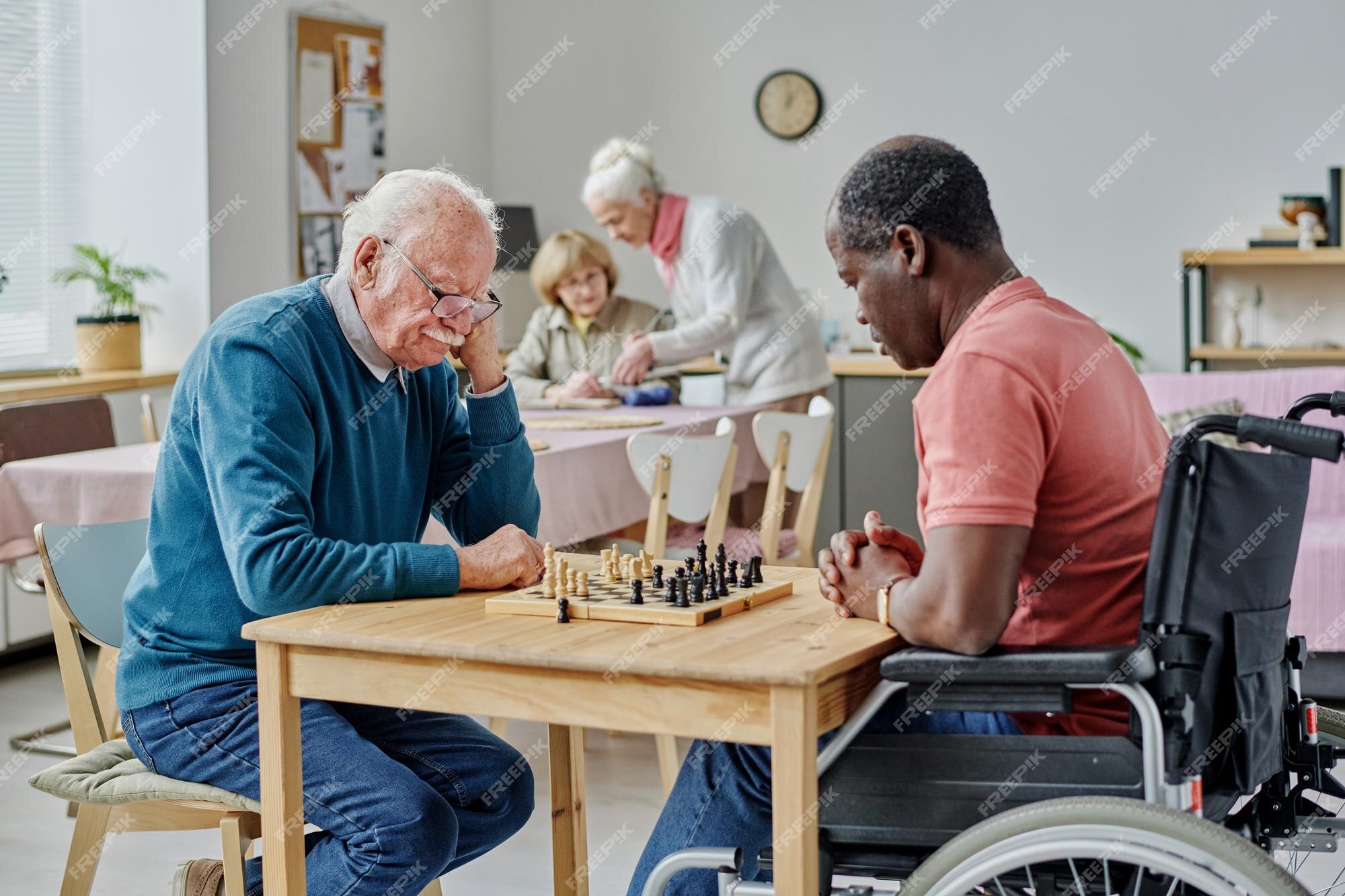 Menino com deficiência jogando xadrez com um amigo jogador com