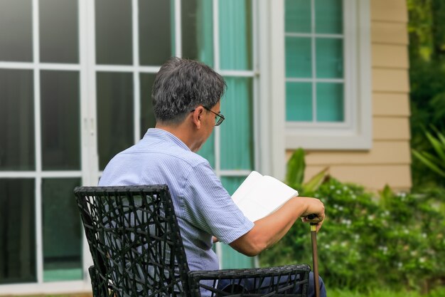 Homem sênior lendo e relaxando no quintal