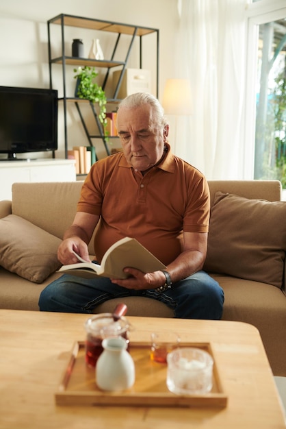 Homem sênior lendo livro cativante