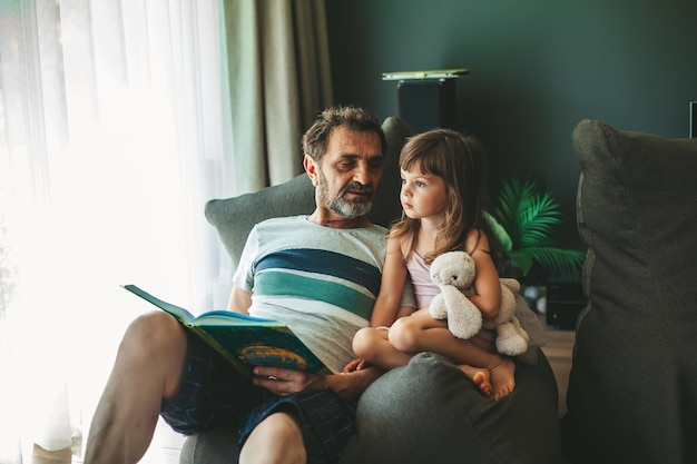 Homem sênior lendo um livro para sua neta