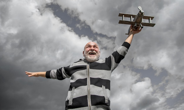 Homem sênior mais velho no fundo do céu homem sênior na aposentadoria homem aposentado sênior com avião de brinquedo