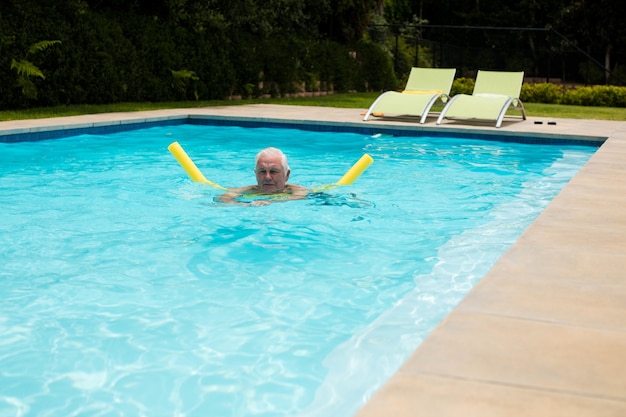 Homem sênior nadando com tubo inflável na piscina