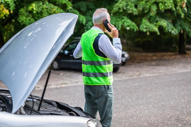 Homem sênior pedindo ajuda após avaria do carro.