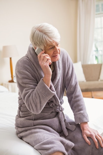 Homem sênior que faz um telefonema na cama