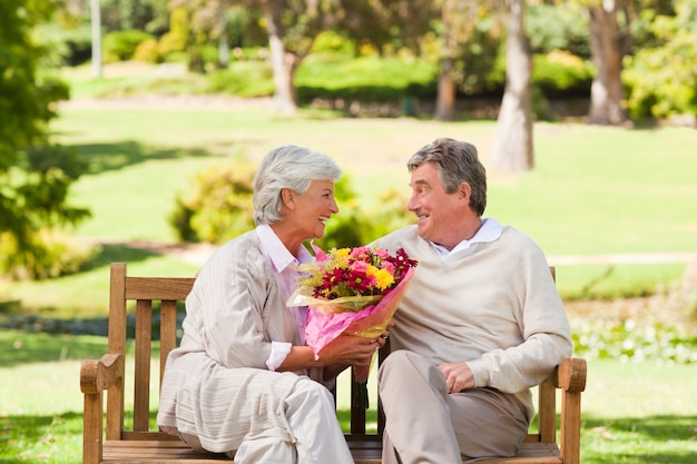 Homem sênior que oferece flores a sua esposa