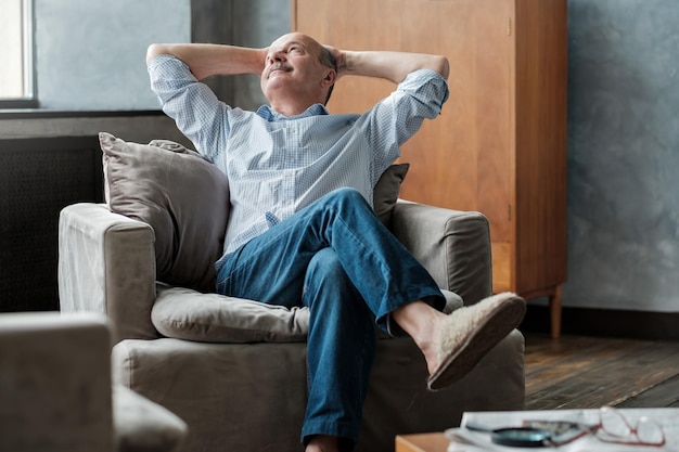 Homem sênior relaxando no sofá em casa sentado sozinho