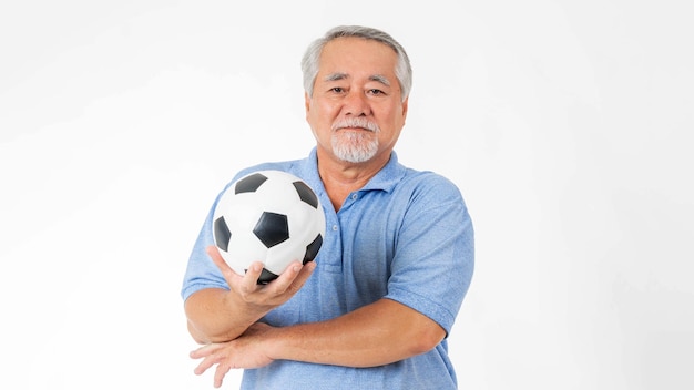 Homem sênior saudável com estilo de vida segurando uma bola de futebol e se preparar para o favorito do time de torcida isolado no fundo branco