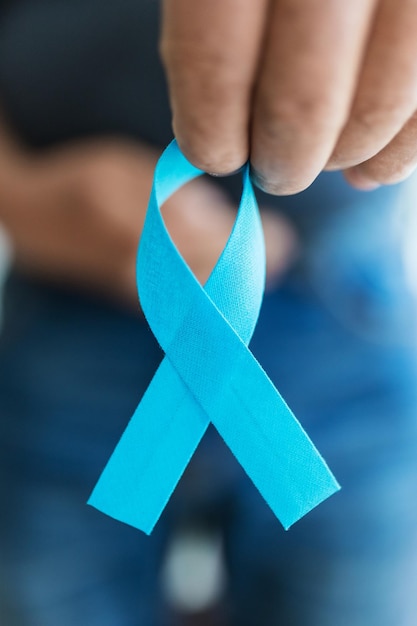 Homem sênior segurando uma fita azul de conscientização do câncer