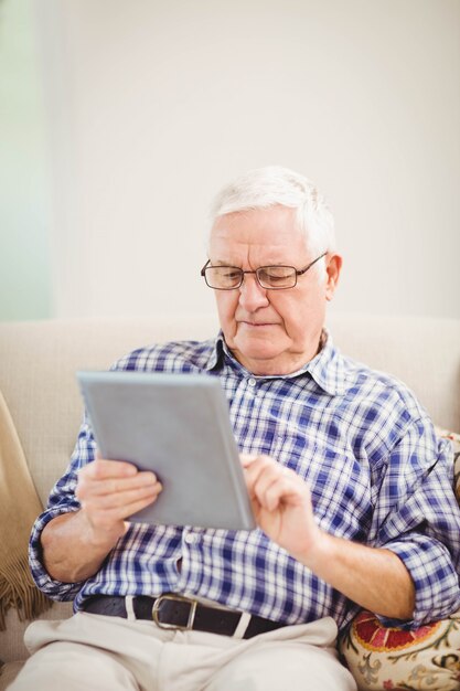 Homem sênior, sentar sofá, e, usando, tablete digital, em, sala de estar