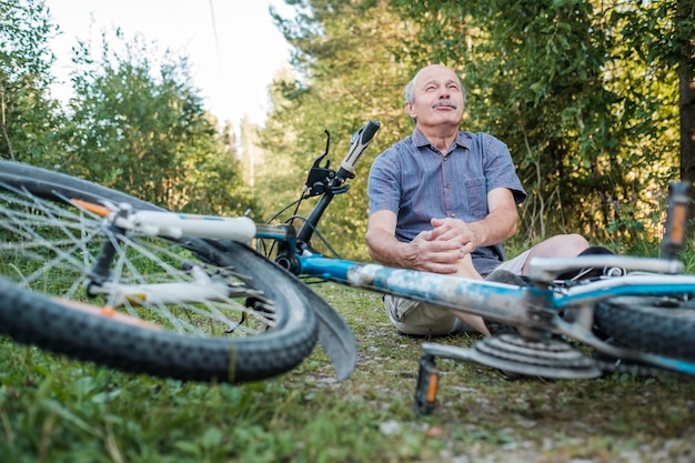 Homem sênior tem uma dor depois que ele caiu de sua bicicleta