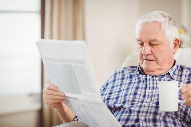 Homem sênior, tendo, um, xícara café, e, jornal leitura, em, sala de estar