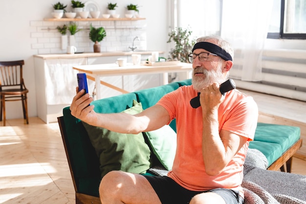 Homem sênior tomando selfie para rede social durante exercícios de fitness com halteres bem-estar