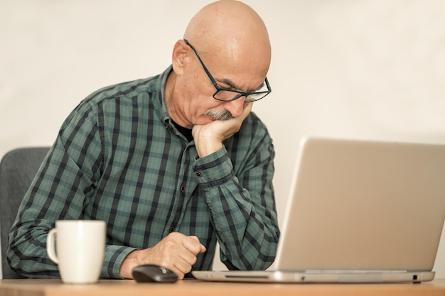 Homem sênior trabalhando com laptop em casa