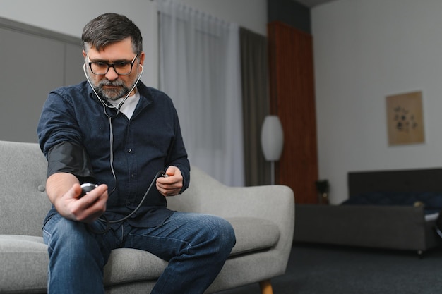 Homem sênior usando dispositivo médico para medir a pressão arterial