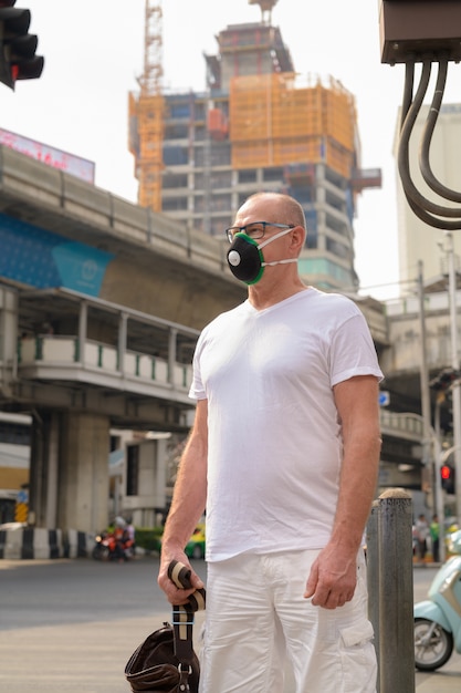 Homem sênior usando máscara facial para se proteger da poluição atmosférica na cidade