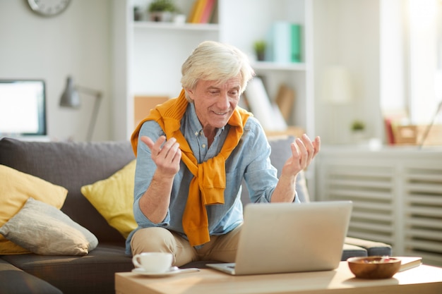 Homem sênior usando o laptop em casa