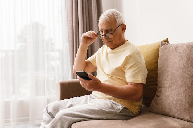 Homem sênior usando óculos está usando smartphone