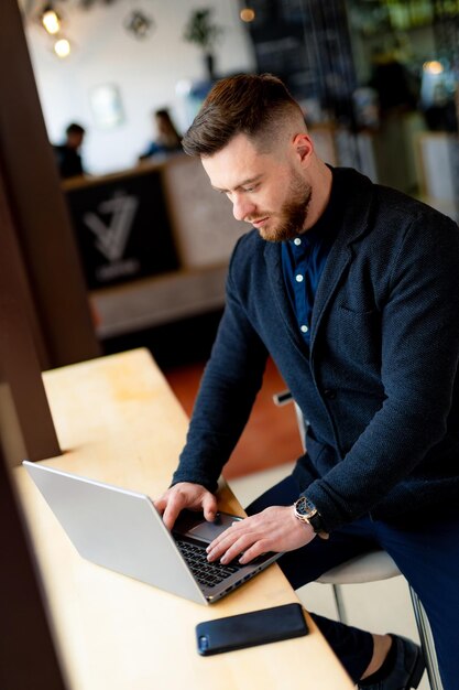 Foto homem sentado à mesa com laptop e telefone celular