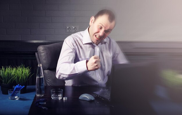 Homem sentado à mesa trabalhando em um laptop