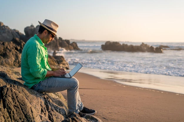 Homem sentado com um laptop sozinho na praiax9