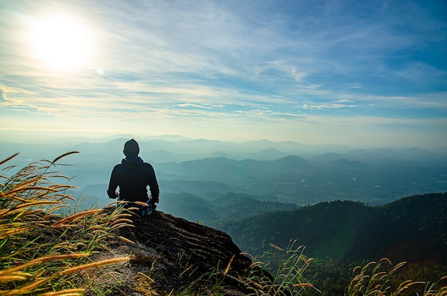 Homem sentado e observando a bela vista ao nascer do sol