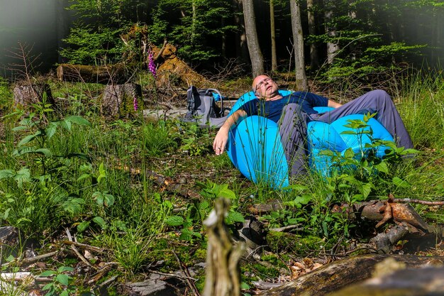 Foto homem sentado em um assento inflável na floresta