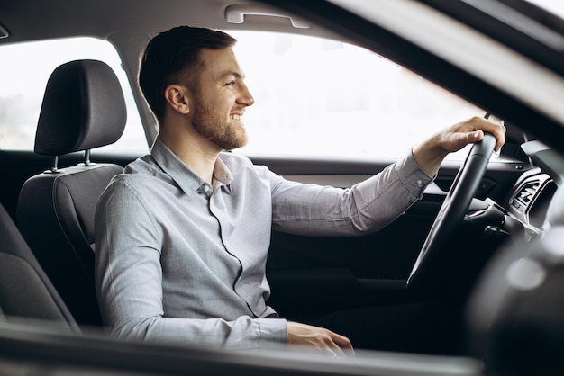 Homem sentado em um carro novo em um showroom de carros