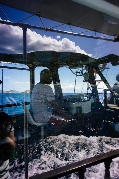 Homem sentado em um navio visto através de uma janela