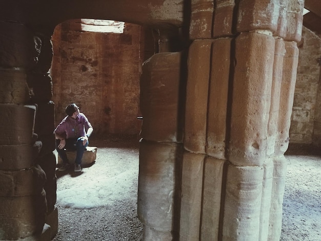 Foto homem sentado em uma caverna antiga