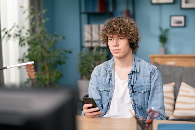 Homem sentado na mesa na sala de estar ouvindo música conceito de fones de ouvido alegre