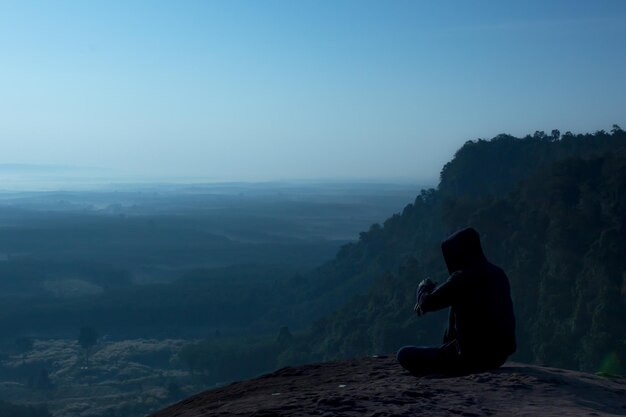 Foto homem sentado na montanha contra o céu