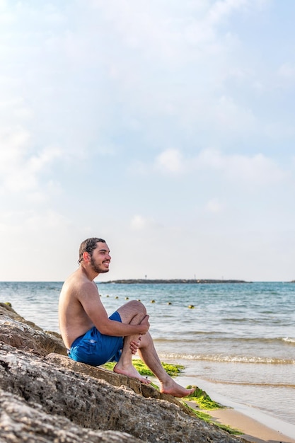 Homem sentado na rocha apreciando a vista para o mar viagens férias turismo ecológico ao ar livre