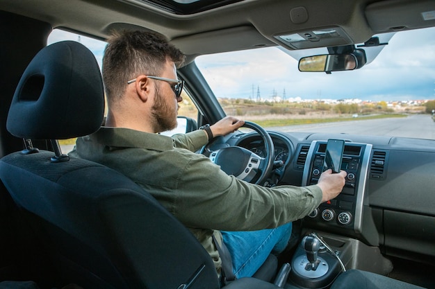 Homem sentado no carro usando o estilo de vida distraído do telefone